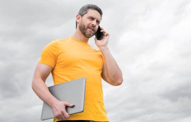 Bilgisayarlı bir adam gökyüzünde akıllı telefondan konuşuyor. modern yaşam.