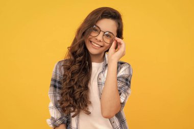 Sarı arka planda damalı gömlek ve gözlüklü mutlu bir çocuk..