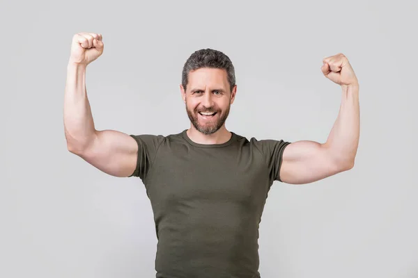 灰色の背景で隔離された筋肉の強い男を成功させた スタジオで強い筋肉質の男 筋骨の強い男の写真だ 強い筋肉マンはTシャツを着て — ストック写真