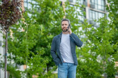 Adamın açık havada akıllı telefon görüşmesi var. Sokakta akıllı telefon görüşmesi yapan bir adam. Adam dışarıdaki akıllı telefondan arıyor. Adamın fotoğrafı. Akıllı telefondan ara ve konuş..