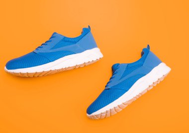 Koşmak için spor ayakkabıları. Bir çift rahat spor ayakkabı. Spor mavi spor ayakkabılar. Sarı arka planda ayakkabılar. Ayakkabı dükkanı. Alışveriş konsepti. Eğitim için ayakkabılar.