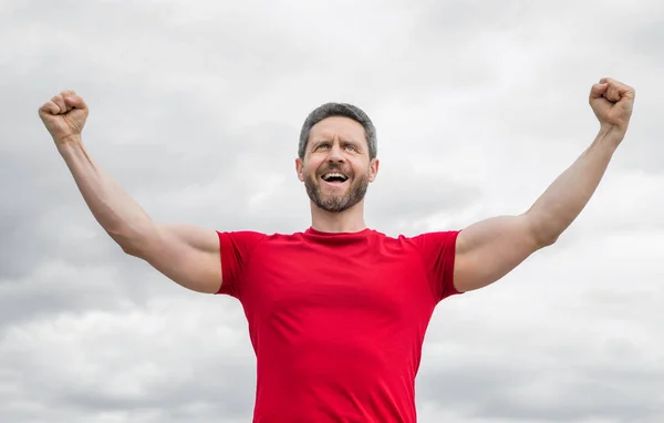 Stock image successful man in red shirt outdoor on sky background.