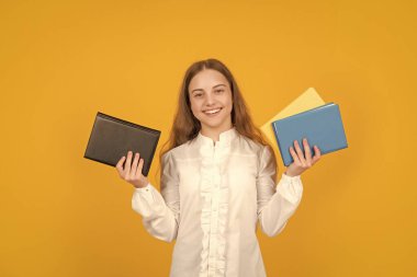 Gülümseyen genç kız sarı arka plan ders kitabını tut, çalış.