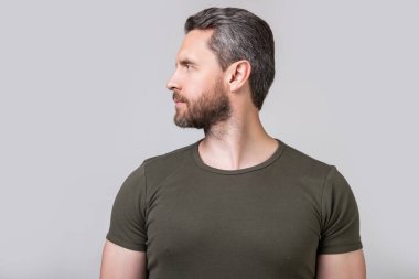 Beyaz adamın sakallı yüzünün profil fotoğrafı. Kirli sakallı beyaz adam tişört giyiyor. Gri arka planda sakallı beyaz bir adam var. Stüdyoda sakalı olan beyaz bir adam..