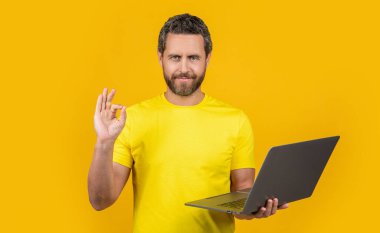 Stüdyodaki adam programcı, tamam. Dizüstü bilgisayarlı adam programcısının fotoğrafı. İnsan programcısı sarıda izole edildi. Arka plandaki adam programcısı.