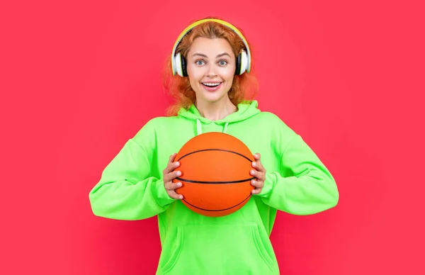 positive basketball woman player isolated on red background. basketball woman player at studio. photo of basketball woman player in hoodie. redhead basketball woman player on color background.