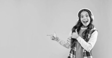 Müzik dinle. Kopyalama alanını işaret ediyor. Yeni teknoloji. Çocukluk gelişimi. Modern kulaklıklı çocuk. Online eğitim. Okula dönüyorum. Kulaklıklı genç kız hayrete düştü. Müzik aşığı.