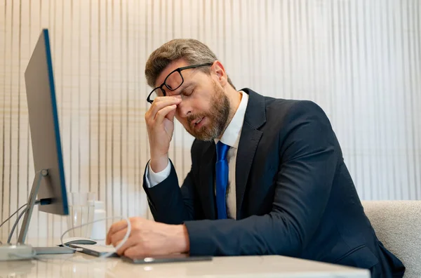 overworked tired businessman has migraine pain. photo of tired businessman has migraine. tired businessman has migraine in office. tired businessman has migraine while working.