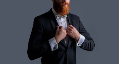 Smokin giymiş bir adamın stüdyosunun görüntüsü. Zarif smokin giyen bir adam. Smokin modası. Smokinli sakallı adam gri arka planda izole edilmiş..