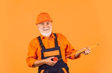 Kıdemli müteahhit ölçü olarak bant hattı kullanır. Ölçüm. Mühendis boyutu. İnşaatçı mezura tutuyor. Mühendislik ve onarım Mutlu marangoz. Duvarı boylayan tamirci..