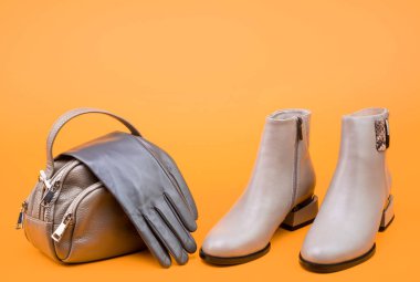 Ayakkabı dükkanı. kopyalama alanı. Kadın derisi şık ayakkabılar. Moda aksesuarı. Bir çift şık deri ayakkabı ve çanta. bej çizmeler ve eldivenler. Sarı arka planda bilek çizmeleri.