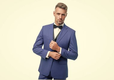 Beyaz arka planda boyun yayı olan mavi takım elbiseli olgun bir iş adamı..