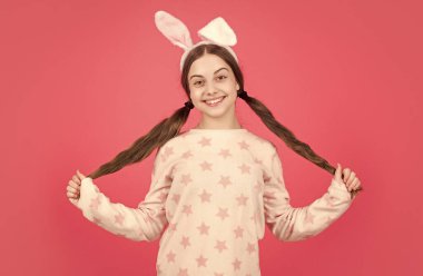 Saçımı seviyorum. Eğlence zamanı. Sevimli çocuk komik görünüyor. Paskalya bahar tatili. Mutlu genç kız tavşan kulağı takıyor. Mutlu Paskalyalar. çocukluk mutluluğu. Tavşan kulaklı ve pijamalı çocuk..