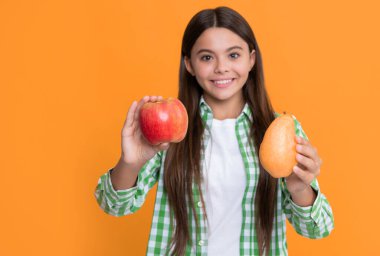 positive kid with apple and pear on yellow background.