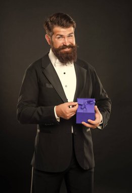 happy man in tuxedo bow tie formalwear on black background with business reward box. occasion greeting.