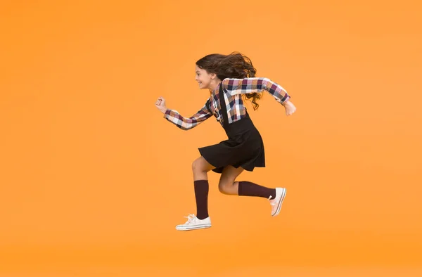 Unstoppable future. Happy girl in midair yellow background. Energetic child run to school. Pursuing future goal. Dynamic movement. Childhood and growing up. I will change the future, copy space.