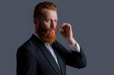 Zarif smokin giyen bir adam. Smokin modası. Smokinli yakışıklı sakallı adam yüzü gri arka planda izole edilmiş. Smokinli bir adamın stüdyosu çekildi..
