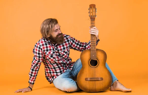 Guitar player on yellow background. Cheerful guitarist. charismatic mature man playing guitar while sitting. relax with favorite music. guy with guitar performing song.