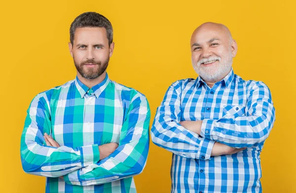 two generation family men isolated on yellow. two generation family men in studio. two generation family men on background. photo of two generation family men wear checkered shirt.