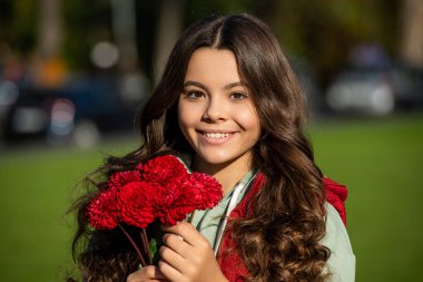 Dışarıda sonbahar buketi olan pozitif bir genç kız. Sonbahar buketli genç bir kızın fotoğrafı. Dışarıda sonbahar buketi olan genç bir kız. Sonbahar çiçekli genç kız buketi.