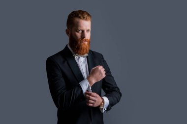 Smokinli beyaz bir adamın stüdyosu çekiliyor. Smokin giyen bir adam. Smokin resmi kıyafet. Smokinli sakallı adam gri arka planda izole edilmiş..