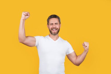 Sıradan giyinen mutlu bir adam. Sarı arka planda izole edilmiş sıradan gömlekli sakallı bir adam. Stüdyoda sıradan bir adam. Beyaz gömlek giyen beyaz bir adamın fotoğrafı..