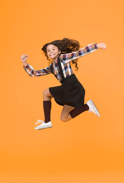 Feel inner energy. Girl with long hair jumping on yellow background. Carefree kid summer holiday. Time for fun. Active girl feel freedom. Fun and jump. Happy childrens day. Jump concept. Break into.