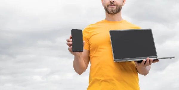 Cropped View Man Presenting Smartphone Laptop Sky Background Copy Space — Stockfoto