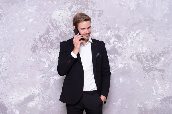 stock image photo of positive business man talk on phone wear suit. successful business man talk on phone isolated on grey. business man talk on phone in studio. business man talk on background.