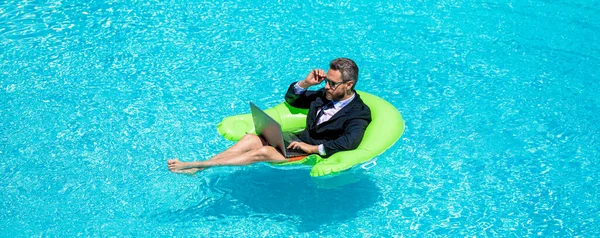 successful man trader work and relax. man trader work and relax in swimming pool. man trader work and relax with laptop. photo of man trader work and relax in pool.