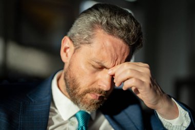 Yorgun iş adamının migren ağrısı var. Hüsrana uğramış iş adamının fotoğrafı migren yapar. Hüsrana uğramış iş adamının evde migreni var. Hüsrana uğramış iş adamının gün boyunca migreni tutar..