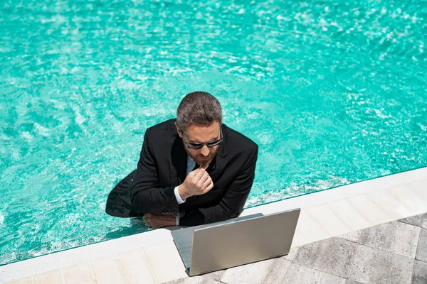 busy businessman has freelance business online. businessman has freelance business in swimming pool. businessman has freelance business with laptop. photo of businessman has freelance business in pool