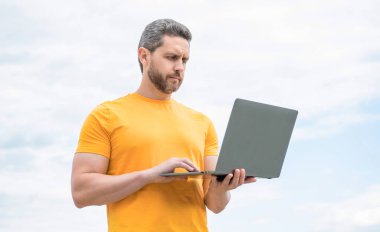 man working online on laptop on sky background.