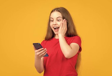 Sarı arka planda akıllı telefonu olan hayret verici bir kız..