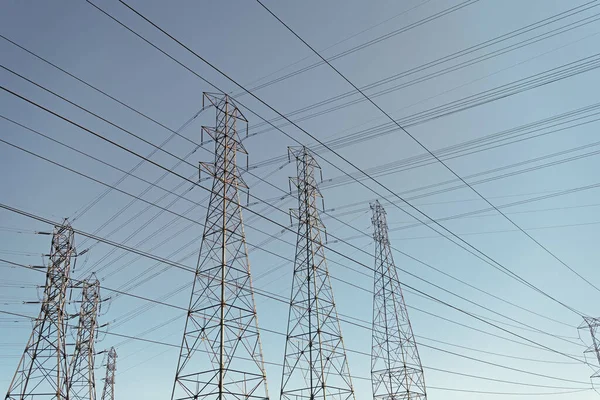 青い空の背景にある電力塔に電圧伝送でエネルギーを生み出す送電線誰も電気を持たない — ストック写真