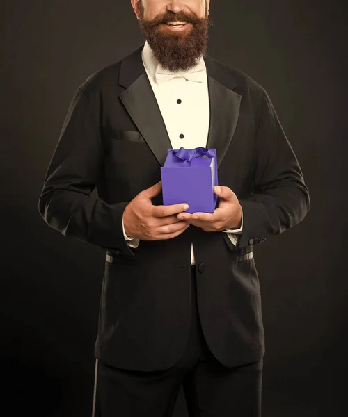 stock image cropped happy man in tuxedo bow tie formalwear on black background with box. shopping sale.