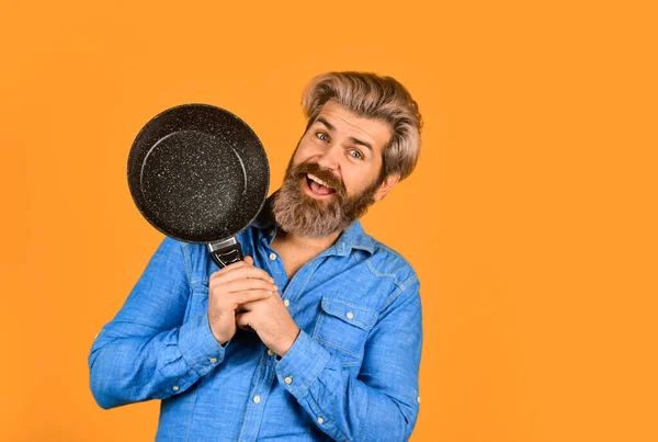 stock image best quality. bearded cook portrait with kitchen tools. bearded man hold cooking pan. cook preparing food in kitchen. husband on kitchen. Cooking food concept. Hold frying pan. Organic food.