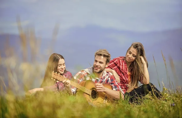 Yakışıklı adam gitar çalarken insanlar dağın tepesinde dinleniyor. Birlikte şarkı söylemek. Müzikal duraklama. Yürüyüş eğlencesi. Huzurlu bir yer. Doğanın melodisi. Yürüyüş geleneği. Müzik eşliğinde yürüyüş yapan arkadaşlar..