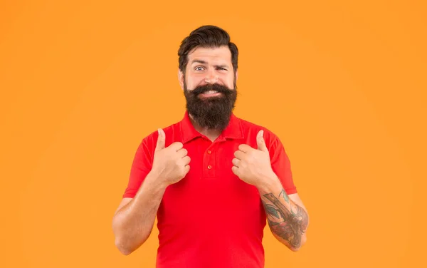 stock image happy bearded man with moustache in tshirt showing thumb up on yellow background, mens beauty.