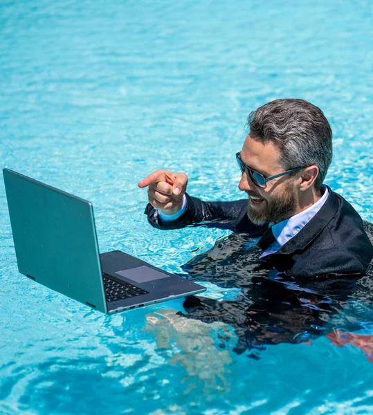 man has business video call in weekend, point finger. man has business video call in weekend refreshing at pool. man has business video call in weekend with laptop. photo of man has business call
