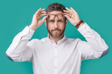 Kafkasyalı olgun bir adamın göz giysisindeki fotoğrafı. Adam mavi arka planda izole edilmiş göz giysisine bak. Olgun bir adam stüdyoda gözlük giyer. Adamım, gözlüklerine bak..