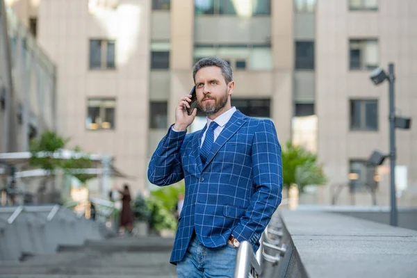 businessman has phone call outdoor. businessman having phone call in the street. businessman call on phone outside. photo of businessman call on phone and talk.