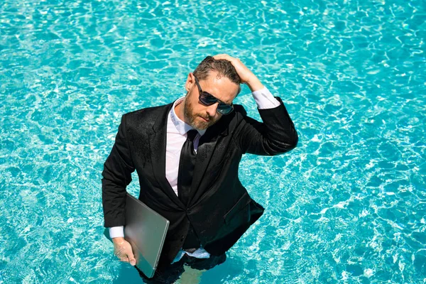 businessman has freelance business in swimming pool. businessman has freelance business with computer. photo of businessman has freelance business in pool. businessman has freelance business online.