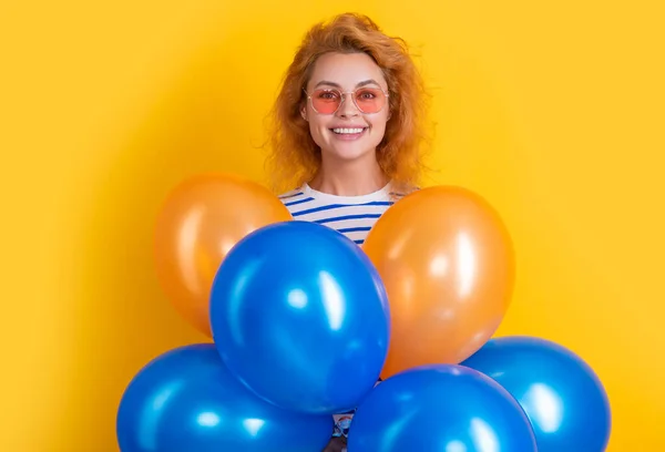 party woman with balloon in sunglasses. happy woman hold party balloons in studio. woman with balloon for party isolated on yellow background.
