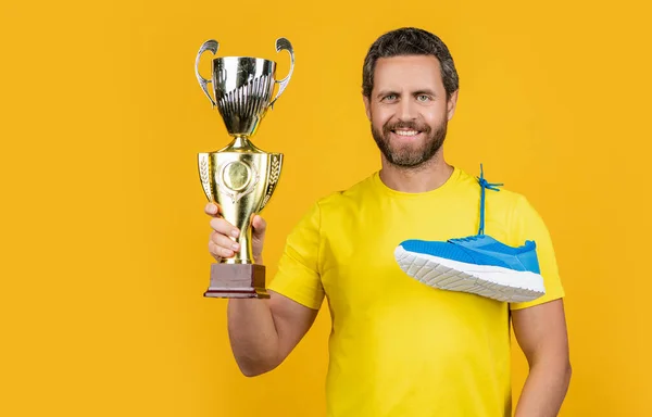 stock image smiling champion man winner on background. champion man winner in studio. photo of champion man winner with sneakers. champion man winner isolated on yellow.