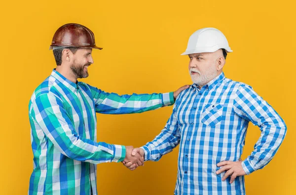 快乐的伴侣男人在背后握手 男伴握手时戴建筑头盔的照片 男人用黄色隔离的方式握手 男伴在演播室握手 — 图库照片