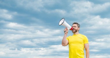 Sarı gömlekli adam arkaplanda hoparlörden seslen..