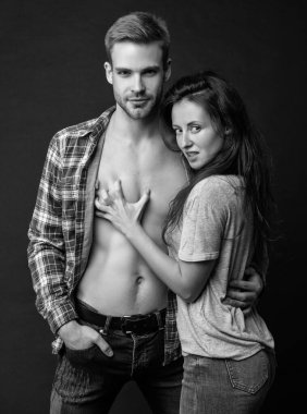 Birbirine aşık seksi genç çift, siyah arka planda, birliktelikte arzu hisseder..