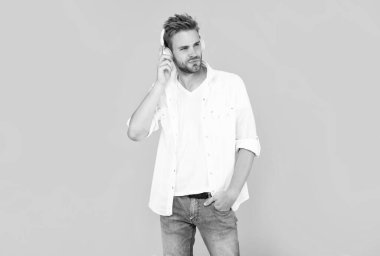 Beyaz tişörtlü adam sarı arka planda kulaklık takıyor..