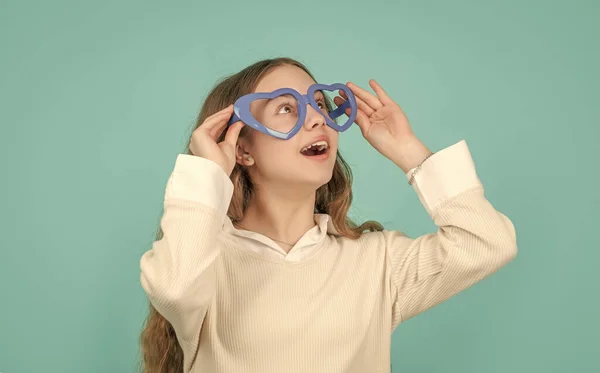 Surprised Child Looking Big Funny Heart Shaped Glasses Blue Background — стоковое фото